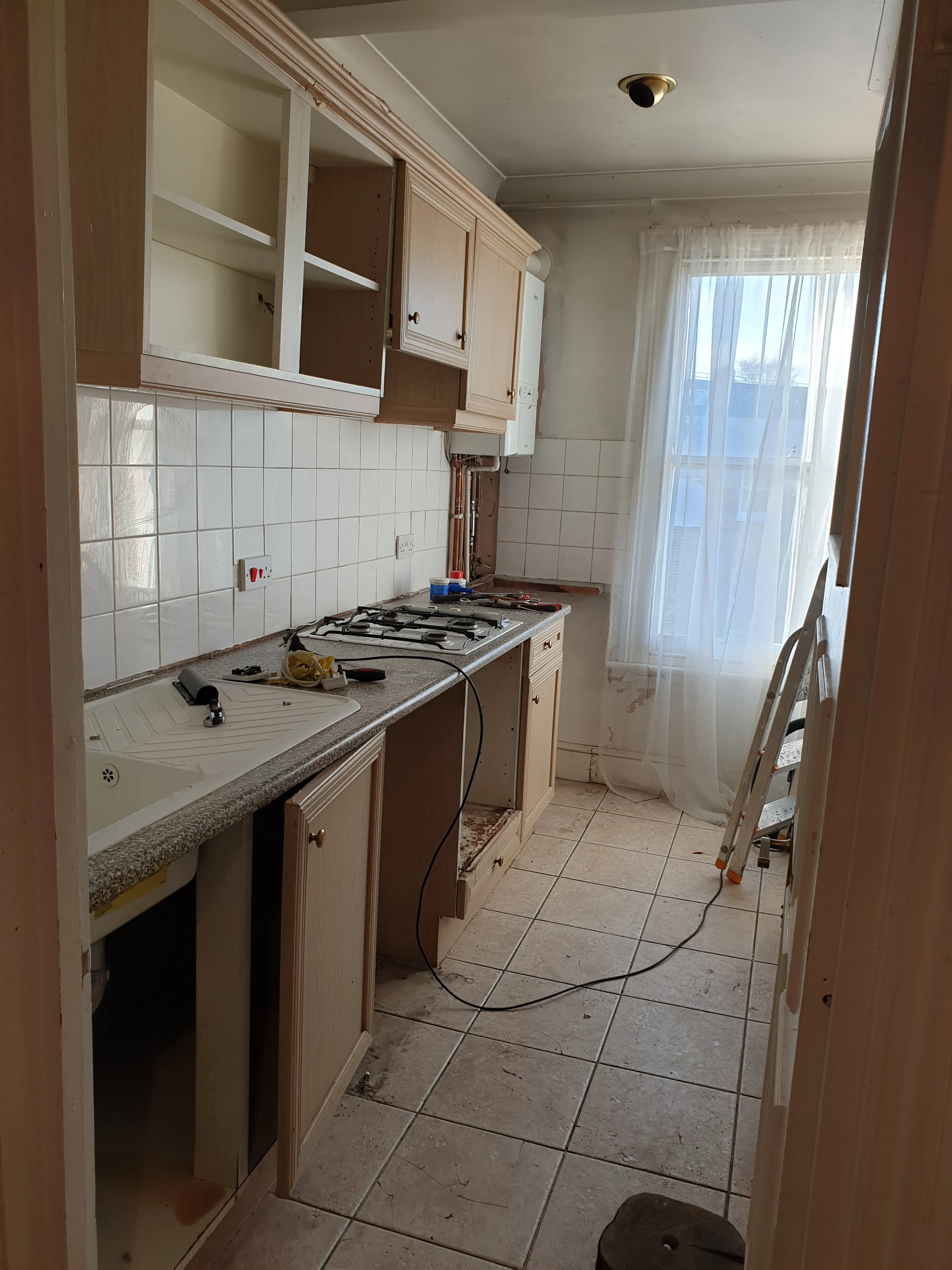 Kitchen before renovation - old cabinetry with dated tiles